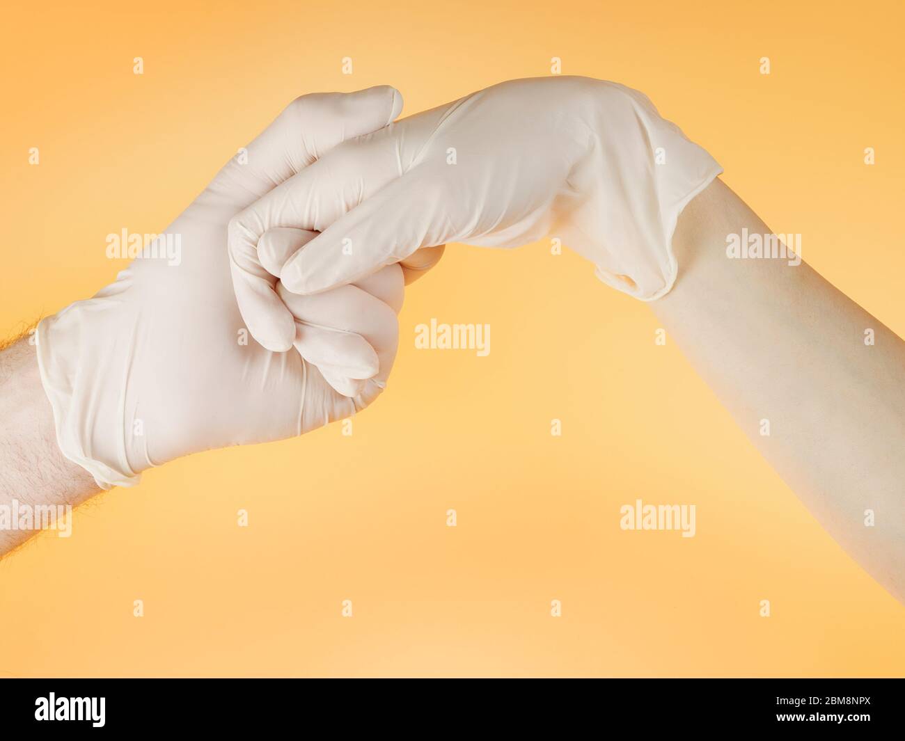 Homme et femme mains dans des gants de protection blancs se tenant l'un l'autre. Sur fond jaune clair Banque D'Images