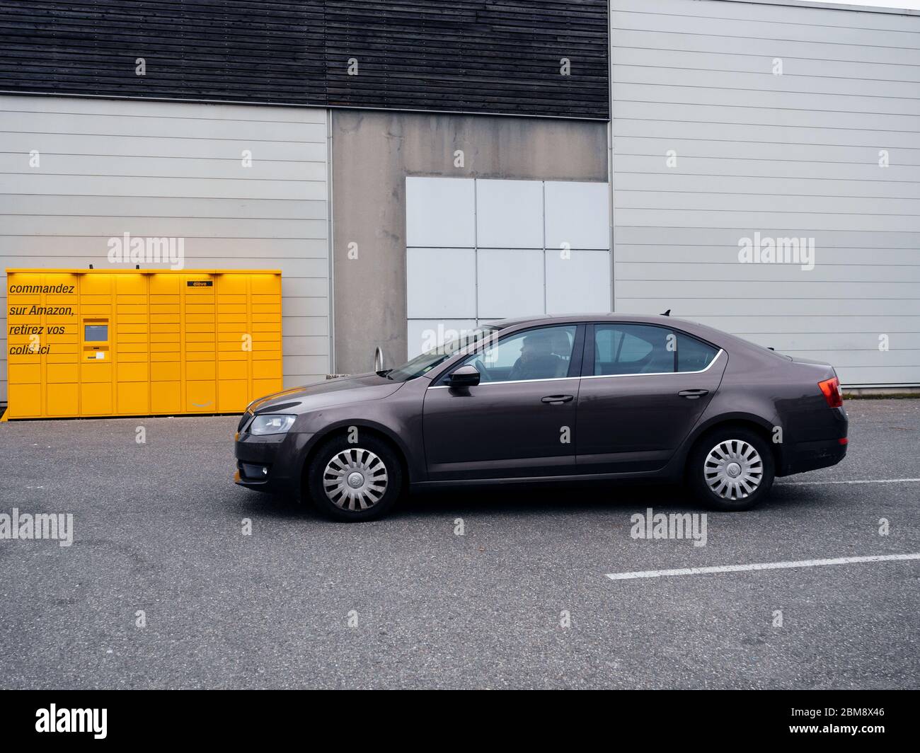 Paris, France - 29 mars 2020 : vue latérale d'une nouvelle voiture marron  Skoda Octavia en face d'Amazon Locker jaune - Service de livraison de colis  en libre-service offert par le distributeur