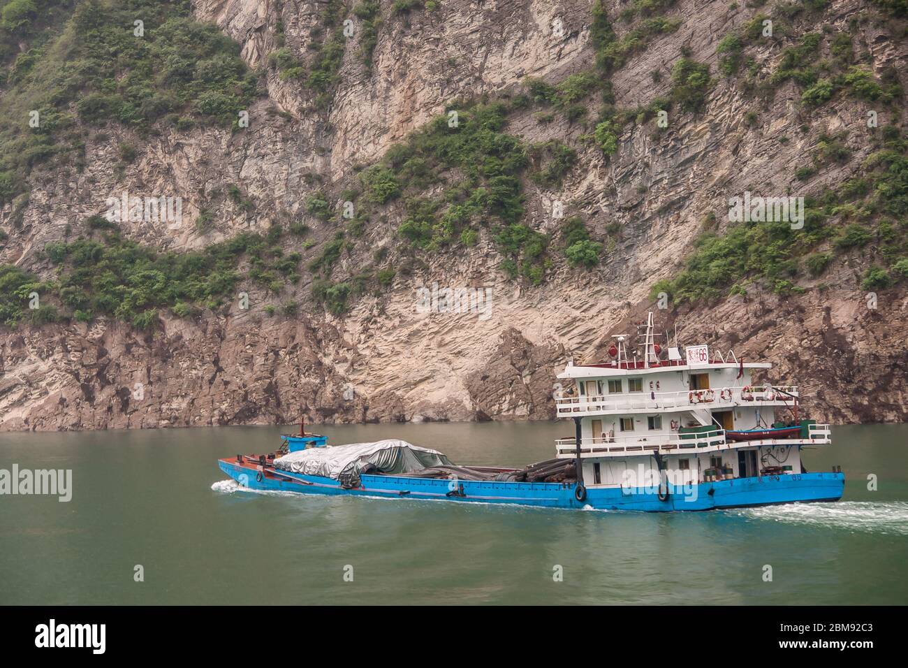 Xiangxicun, Chine - 6 mai 2010 : gorge de Xiling sur le fleuve Yangtze. Profond dans l'eau verte voile bleu et blanc barge couvrant partiellement sa charge avec des bâches. Banque D'Images