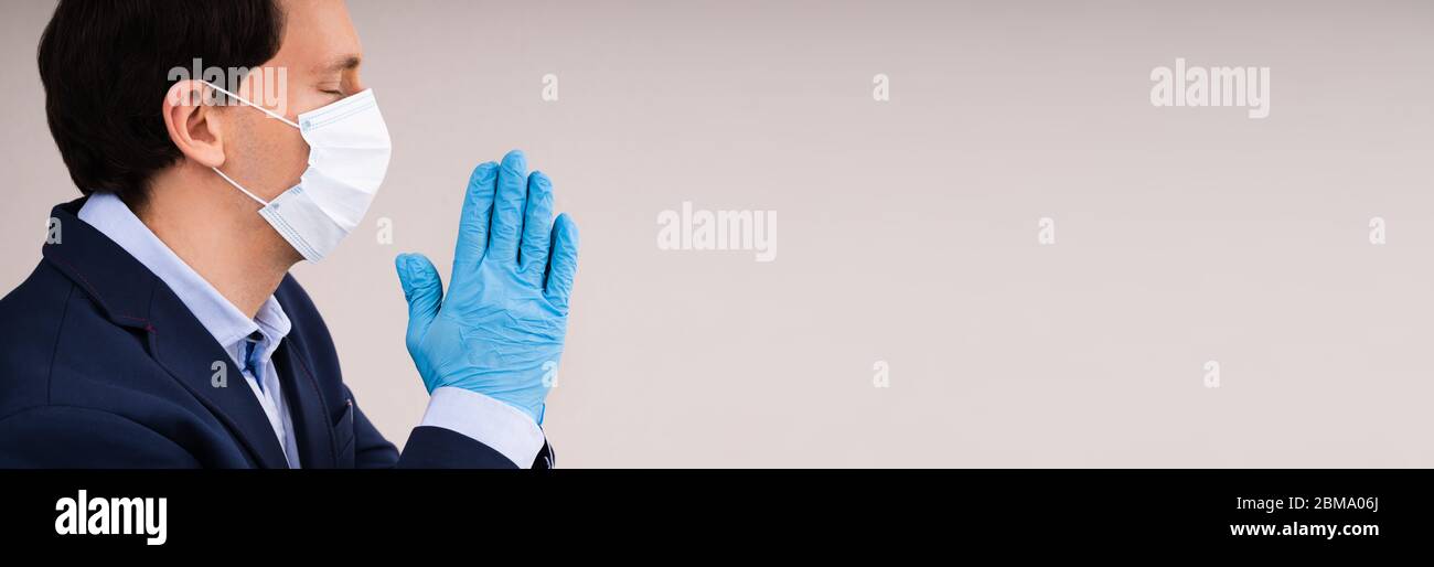 Homme en gants et masque priant pendant une pandémie de coronavirus Banque D'Images