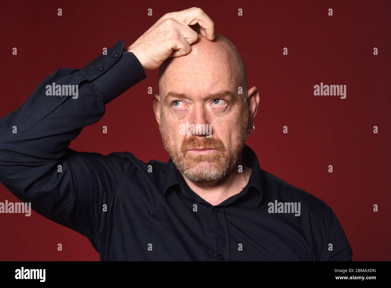 homme avec main sur la tête sur fond rouge Banque D'Images