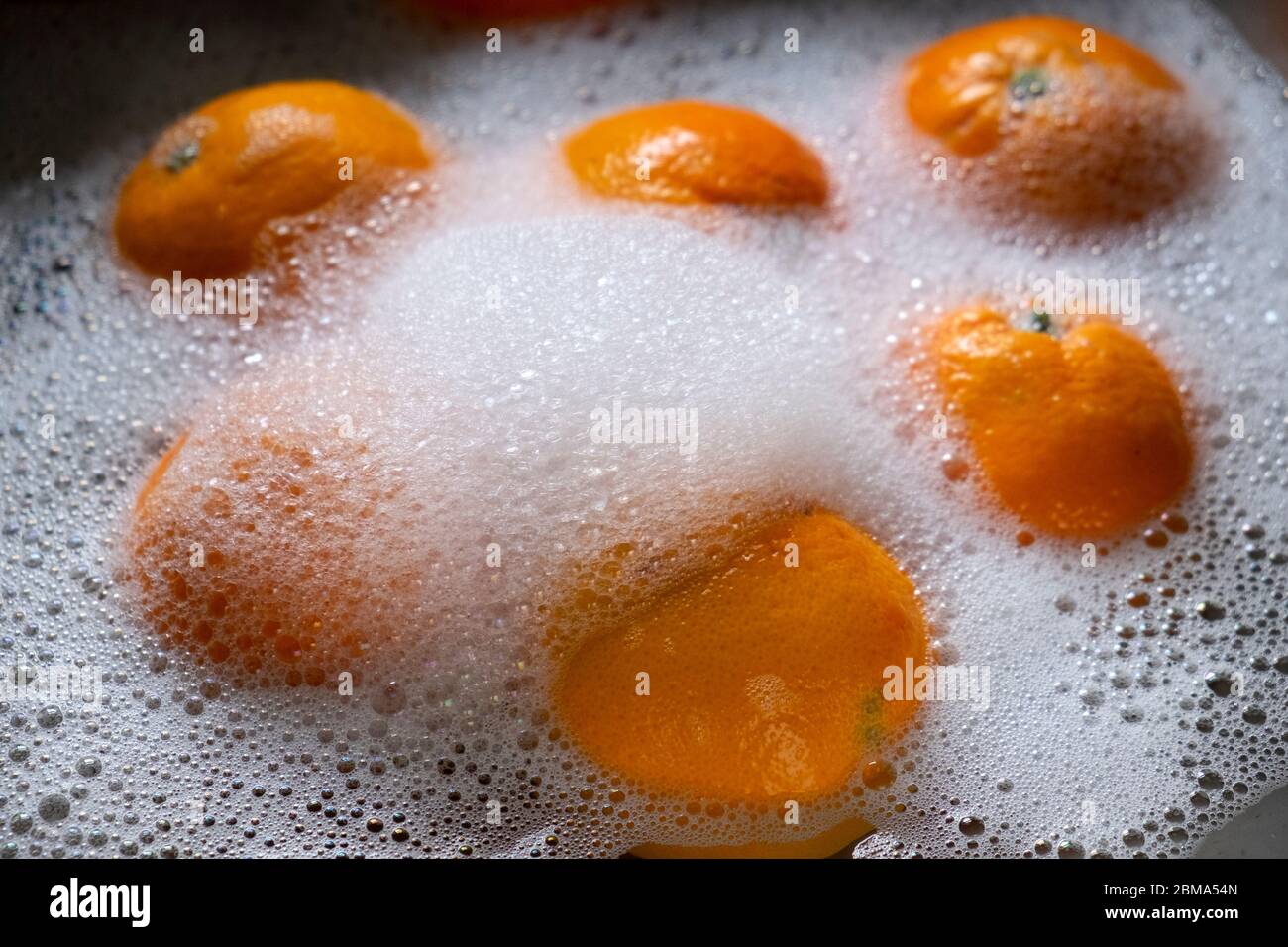 Laver les oranges à la maison dans un évier dans de l'eau savonneuse comme mesure de précaution pour arrêter la propagation du coronavirus Covid 19 pendant la pandémie de 2020 UK KATHY DEWITT Banque D'Images