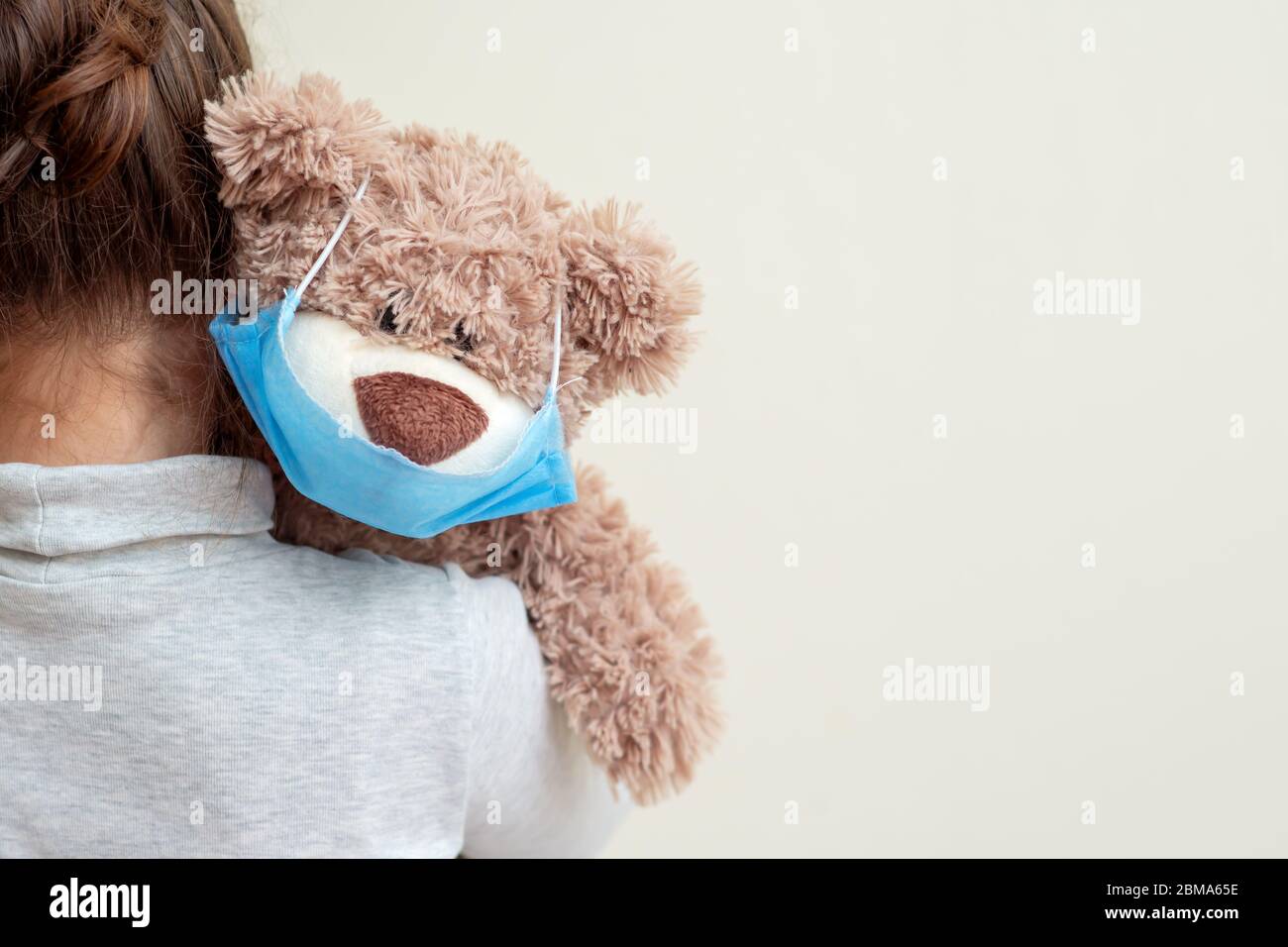 Ours en peluche avec masque médical de protection sur l'épaule de l'enfant. Concept de soins de santé et de protection contre les virus. Banque D'Images