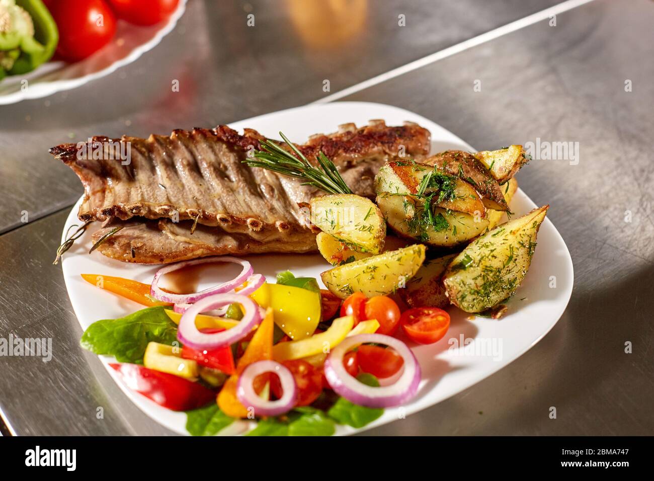 Le chef prépare dans le restaurant. Carré d'agneau grillé avec frites et légumes frais Banque D'Images