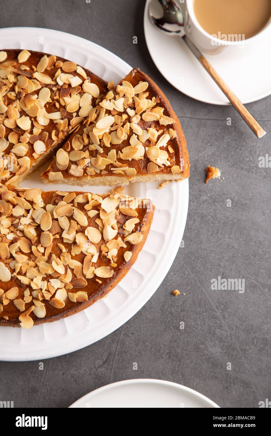 Gâteau aux amandes et au citron avec garniture aux amandes en tranches et une tasse de café sur une surface en béton. Vue de dessus Banque D'Images