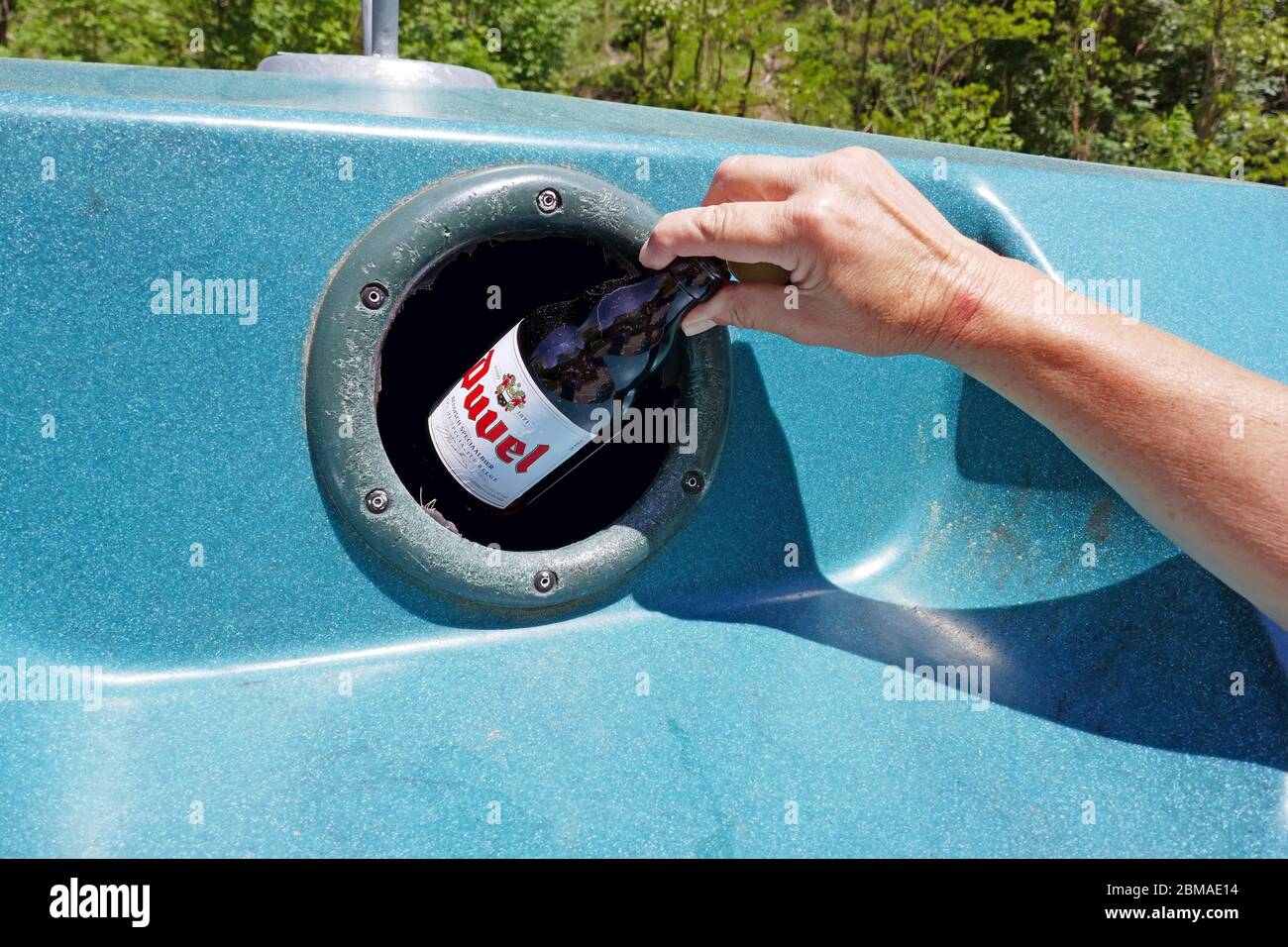 Bouteille en verre avec main femelle placée dans un grand bac de recyclage en plastique dans la région d'Ariège, dans le sud de la France Banque D'Images