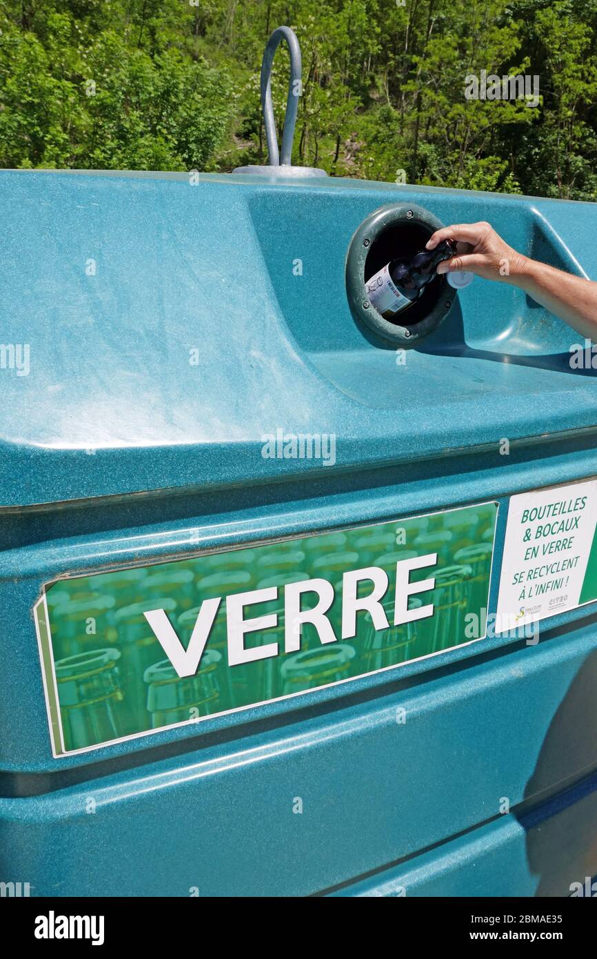 Bouteille en verre avec main femelle placée dans un grand bac de recyclage en plastique dans la région d'Ariège, dans le sud de la France Banque D'Images