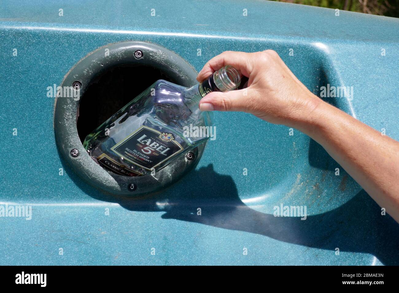 Bouteille en verre avec main femelle placée dans un grand bac de recyclage en plastique dans la région d'Ariège, dans le sud de la France Banque D'Images
