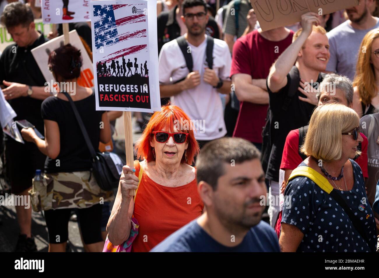 Une femme aux cheveux rouges tenant un panneau indiquant « Refugees In, Fascists Out », lors de la manifestation contre la visite de Donald Trump à Londres Banque D'Images