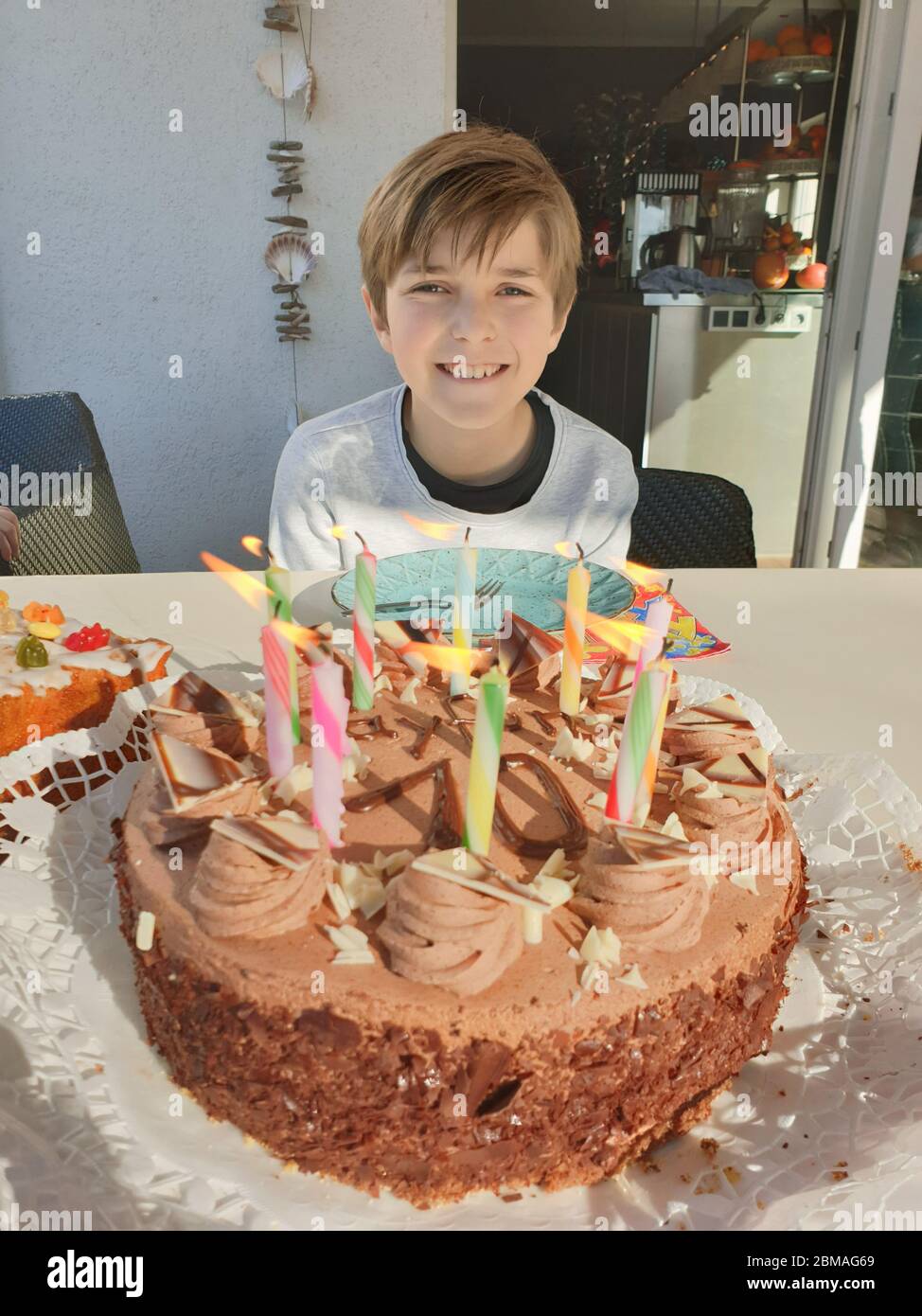 Un garçon d'anniversaire avec un gâteau d'anniversaire et des bougies allumées pour son 10e anniversaire, en Allemagne Banque D'Images