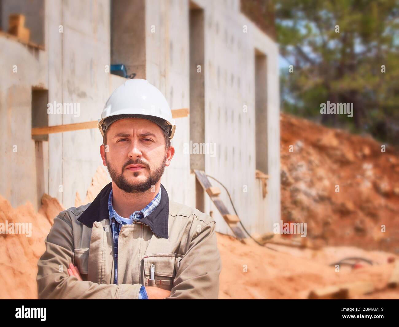 Ingénieur civil caucasien ou ouvrier de construction en casque blanc se tient en face du chantier de construction Banque D'Images
