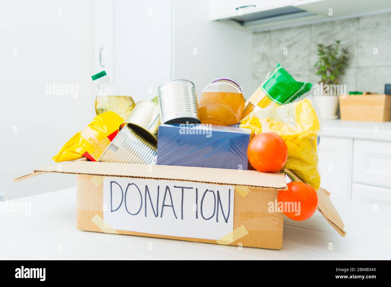 Faire don de nourriture dans une boîte en carton dans la cuisine. Aide pour les personnes en quarantaine. Concept de charité. De nombreux produits gratuitement Banque D'Images