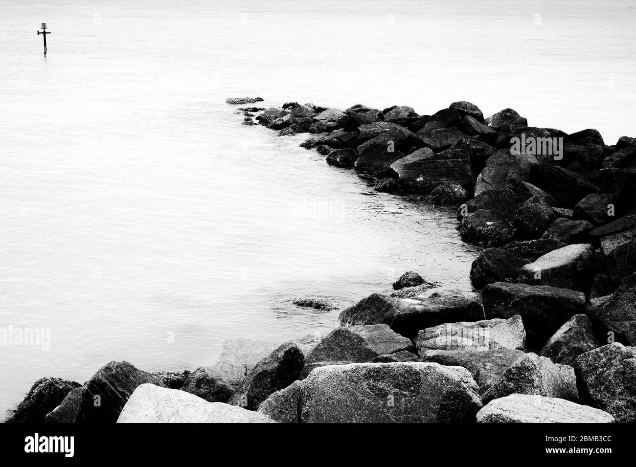 Rochers, la mer et un poste de marqueur, Angleterre Banque D'Images