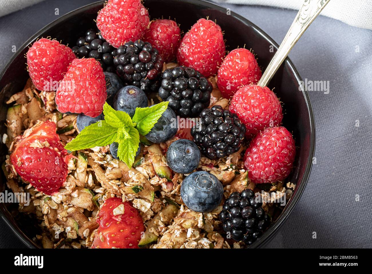 Vue rapprochée du bol petit déjeuner avec céréales, baies et menthe Banque D'Images