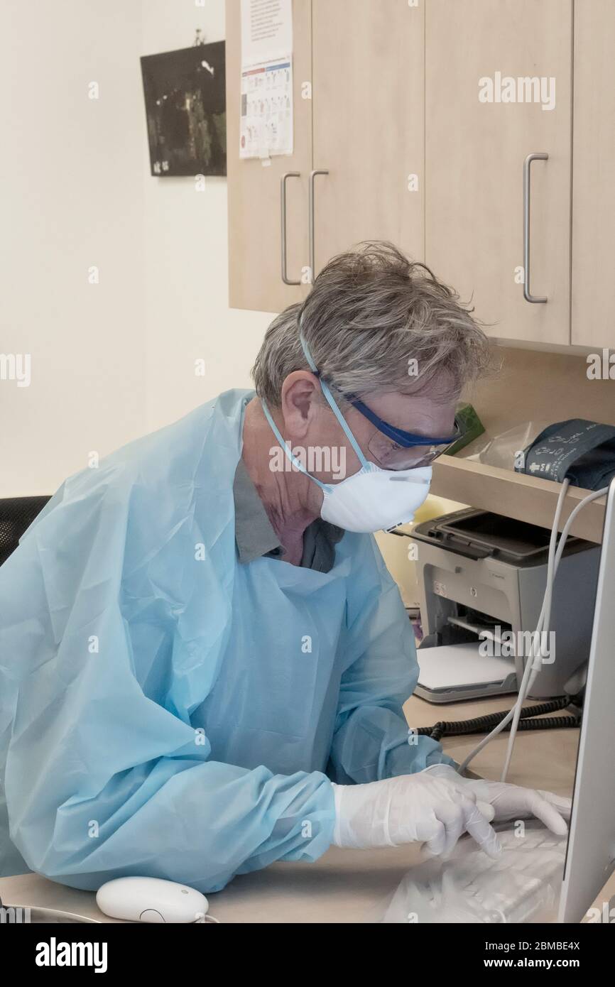 Médecin en pleine tenue pendant l'épidémie de Covid-19 en entrant des informations dans l'ordinateur Banque D'Images