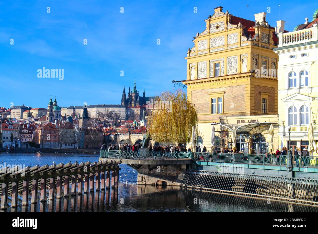 Vue sur la Vltava vers le musée Bedrich Smetana et le centre historique de Prague, avec une foule de touristes visitant la rive. Banque D'Images