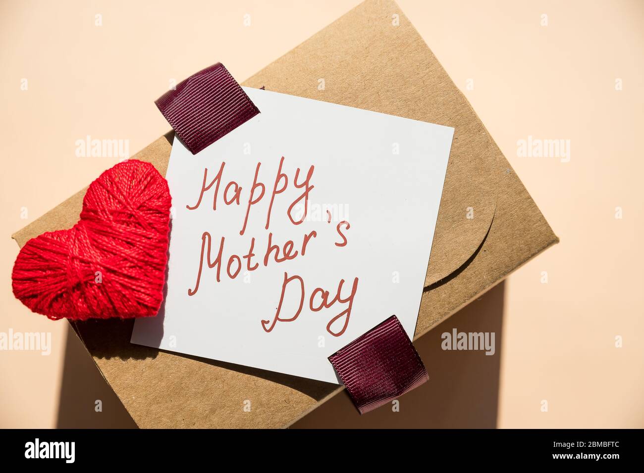 Message de la fête des mères avec cœur fait à la main. Carte de fête des mères.boîte cadeau de vacances sur fond pastel. Banque D'Images