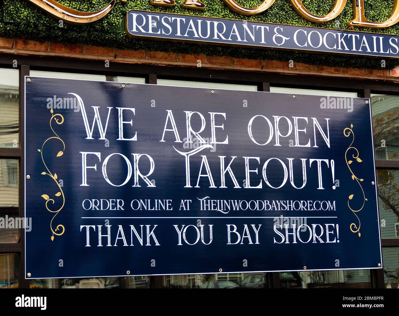 Bay Shore, New York, USA - 18 avril 2020 : une grande enseigne est suspendue dans la fenêtre d'un restaurant lisant nous sommes ouverts pour emporter seulement et merci pendant t Banque D'Images Bay Shore, New York, USA - 18 avril 2020 : une grande enseigne est suspendue dans la fenêtre d'un restaurant lisant nous sommes ouverts pour emporter seulement et merci pendant t Banque D'Images
