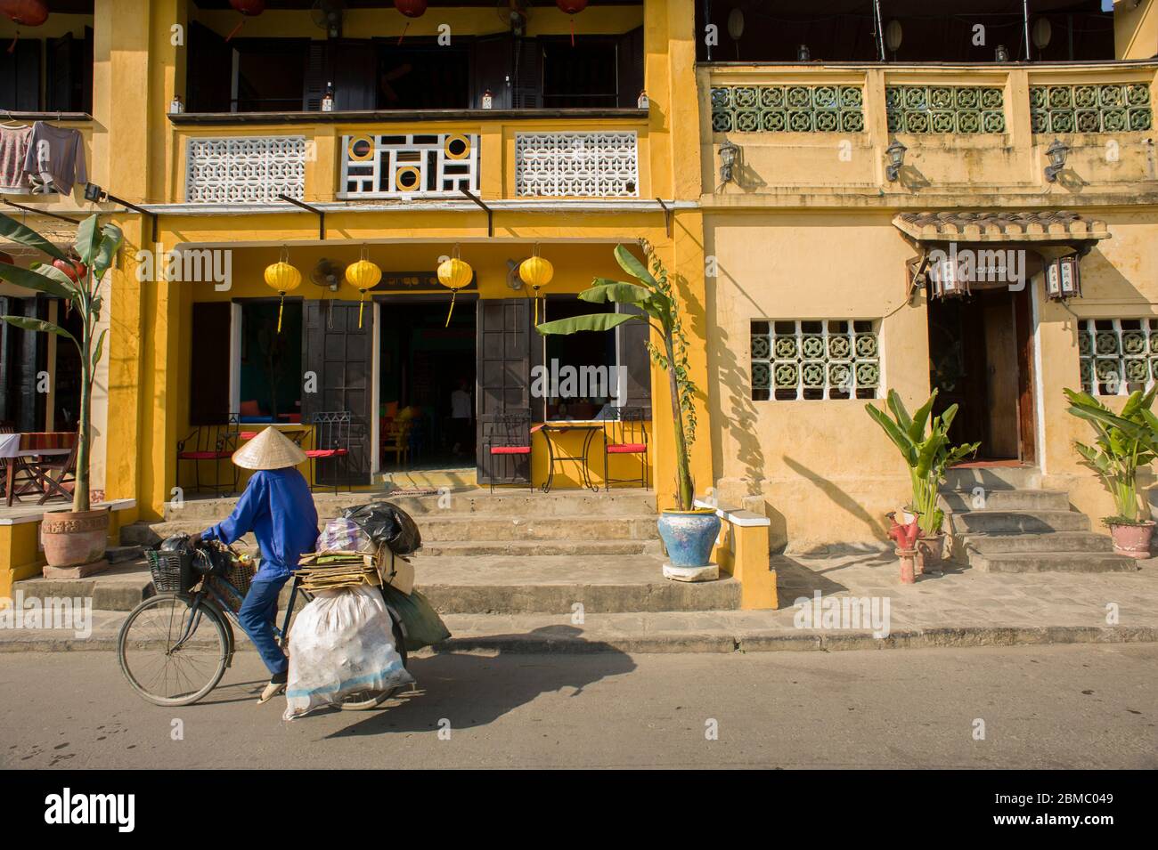 Hoi an, province de Quang Nam, Vietnam - 24 février 2011 : la femme âgée fait des cycles dans le centre historique de Hoi an, et dans ses célèbres maisons coloniales jaunes Banque D'Images