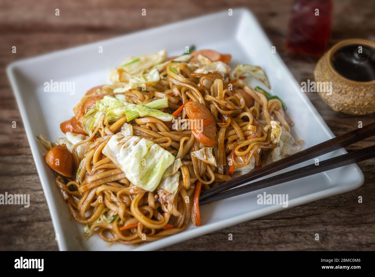 Yakisoba avec saucisse de nouilles japonaises frit avec sauce douce dans la plaque blanche avec éclairage faible soleil. Banque D'Images