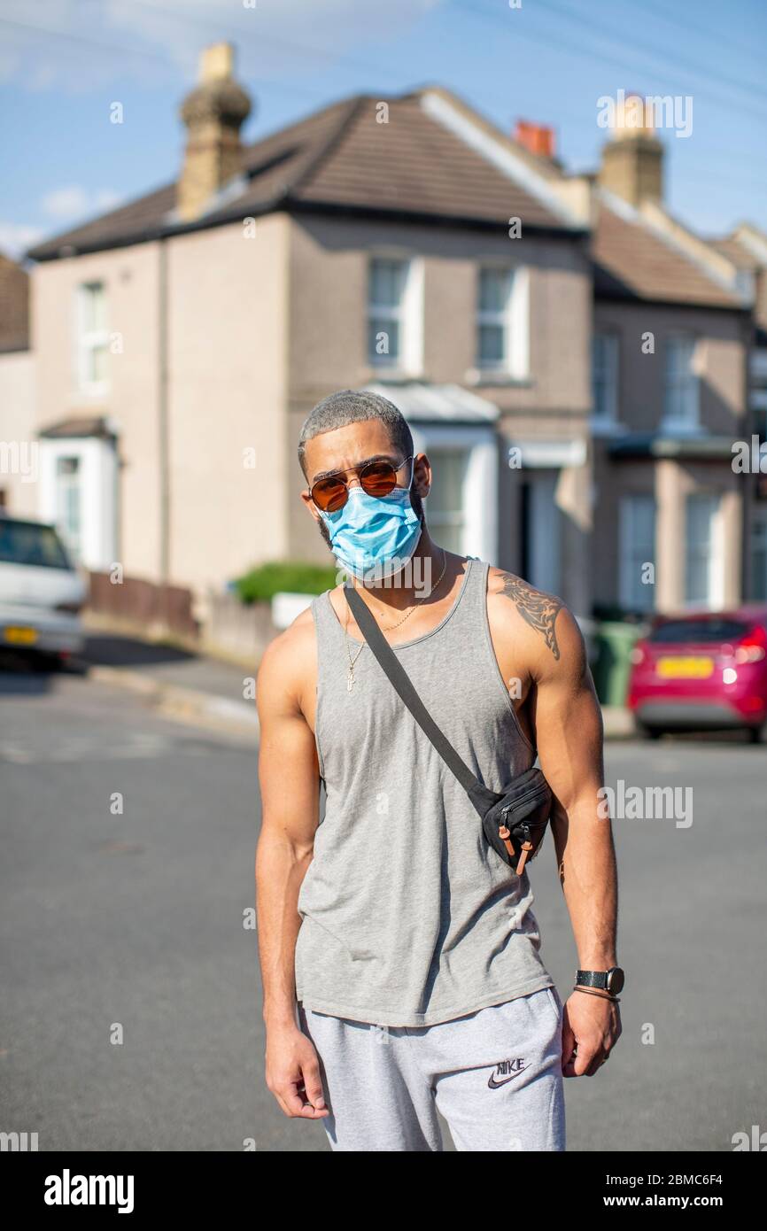 West Norwood, Royaume-Uni. 8 mai 2020. Un jeune homme porte un masque  facial et des lunettes de soleil avec un gilet gris et un bas de  survêtement le 75e anniversaire de la