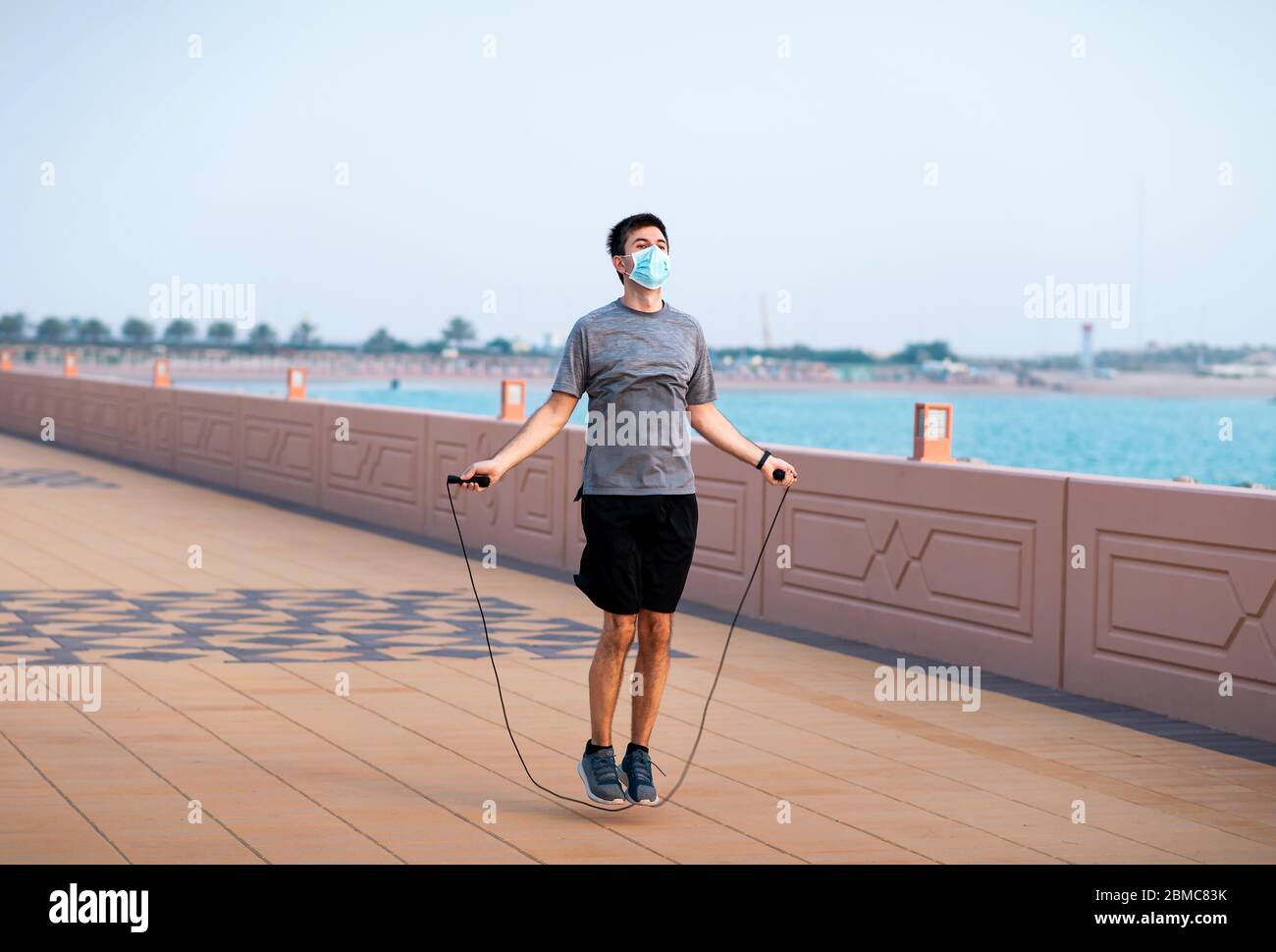 Homme s'exerçant avec une corde de saut et portant un masque chirurgical de protection à l'extérieur Banque D'Images
