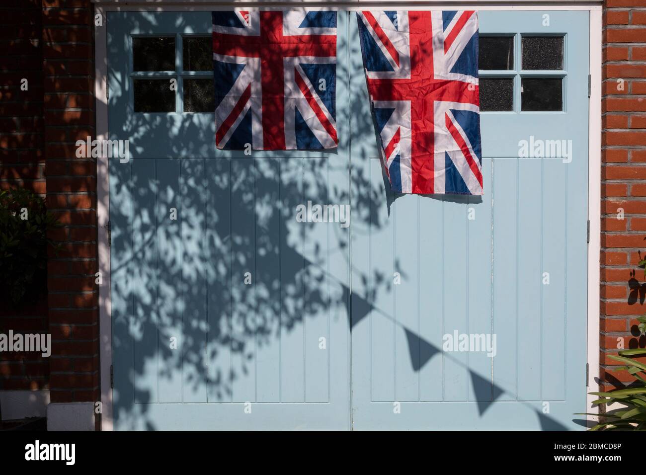 Alors que le blocage du coronavirus se poursuit pendant le May Bank Holiday, la nation commémore le 75e anniversaire de la Ve Day (victoire en Europe Day, le jour où l'Allemagne s'est officiellement rendue en 1945) et à Dulwich, les voisins et les résidents émergent de leur maison à la fête tout en observant les règles de distanciation sociale. Les drapeaux Union Jack pendent d'une porte de garage, le 8 mai 2020, à Londres, en Angleterre. Banque D'Images