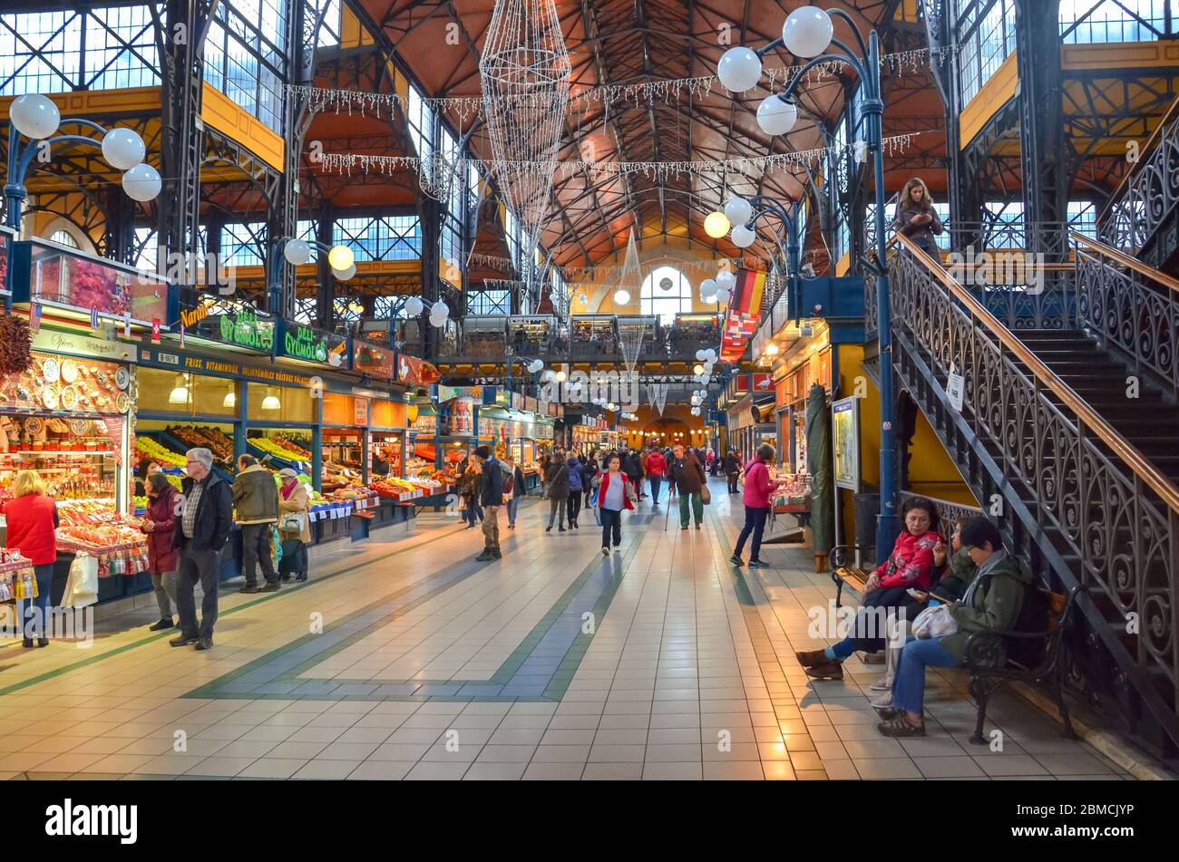 Budapest, Hongrie - 6 novembre 2019 : les gens font du shopping dans la grande salle du marché. Le plus grand marché intérieur de la ville. Les gens magasinent. Marché sous toit. Escaliers menant au deuxième étage. Photo horizontale. Banque D'Images