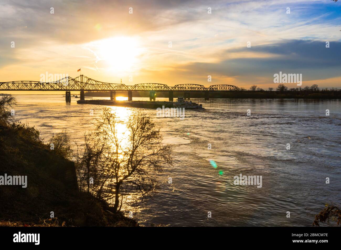 Paysage de coucher de soleil du pont du fleuve Mississippi entre le Mississippi et la Louisiane, à Vicksburg, MS, avec des barges de poussée de remorqueur. Banque D'Images