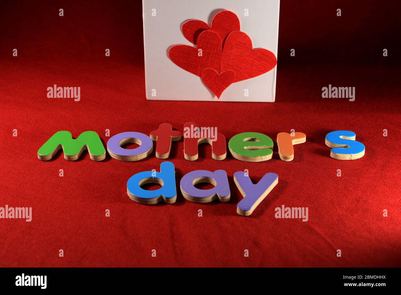 Fête des mères écrite par des blocs d'alphabet colorés disposés sur fond rouge. Boîte cadeau fête des mères. Concept de fête des mères. Message de la fête des mères. Banque D'Images