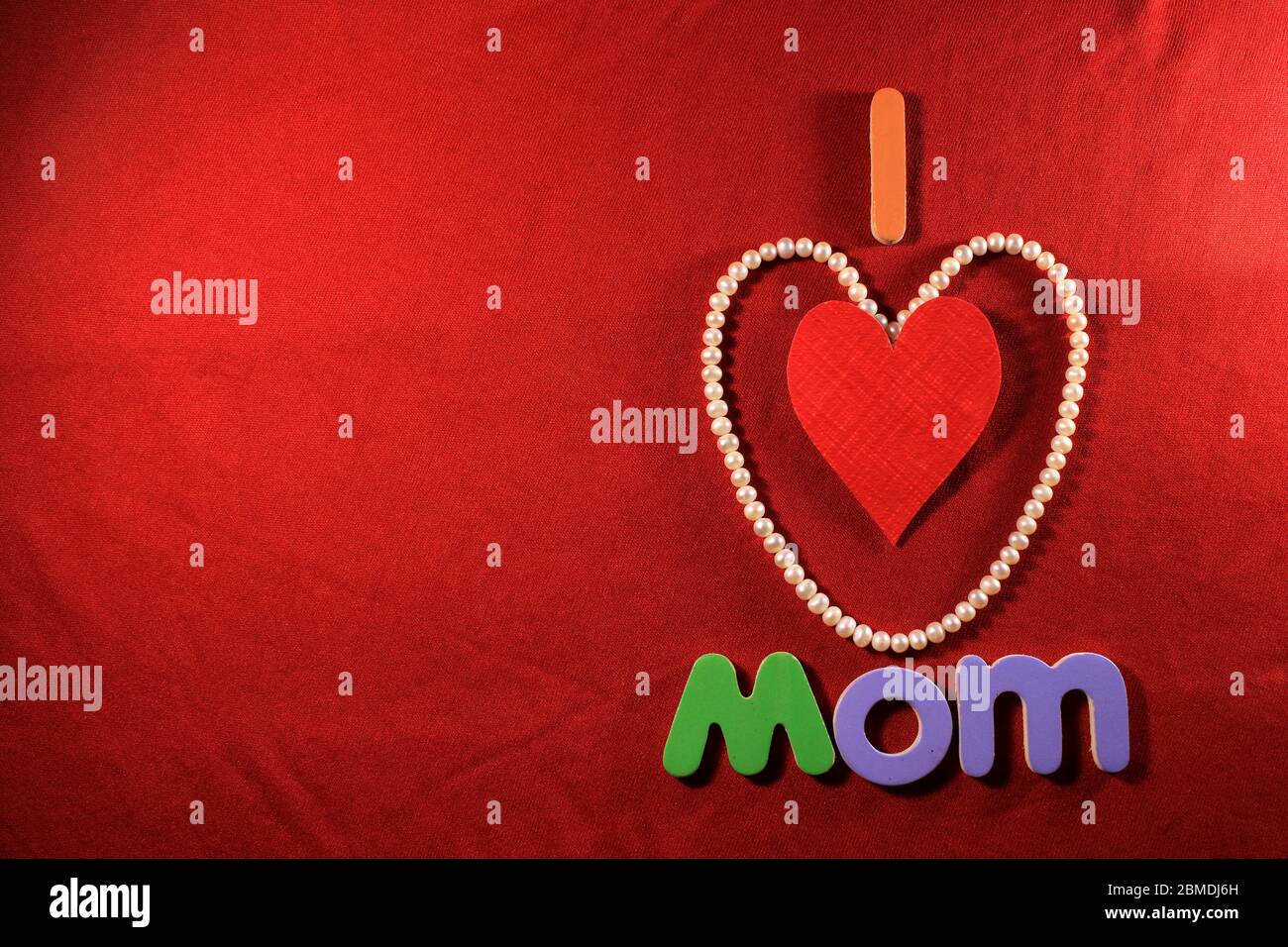Lettres colorées avec ma maman d'amour isolée sur fond rouge de tissu. J'aime maman orthographié avec des lettres colorées et coeur rouge pour la fête des mères. Banque D'Images