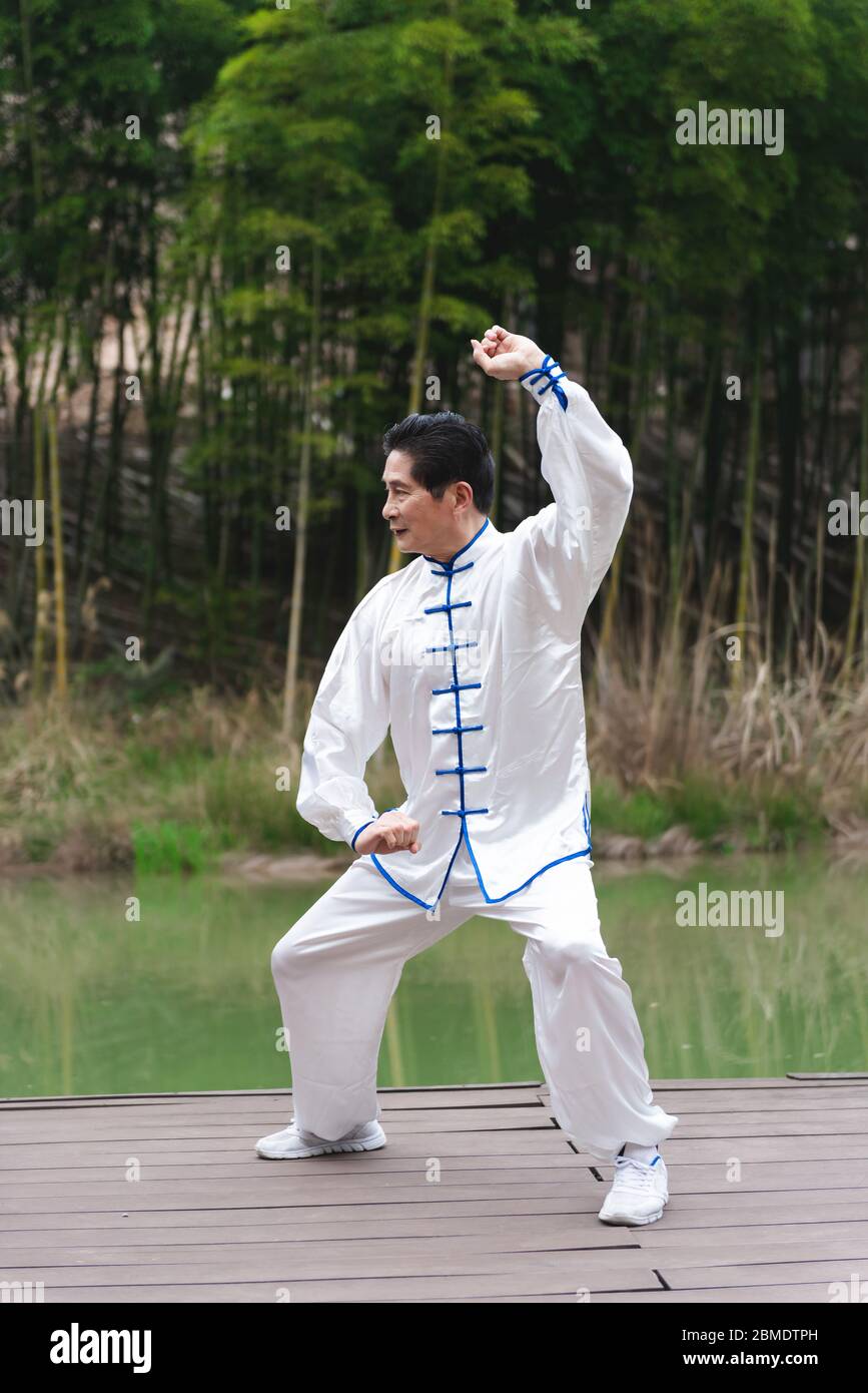 Un homme asiatique âgé faisant du sport au bord du lac Banque D'Images