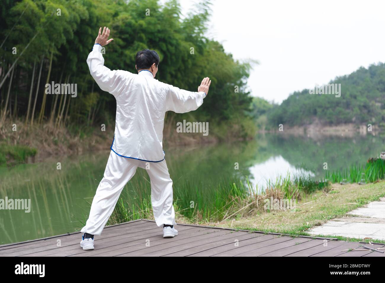 Un homme asiatique âgé faisant du sport au bord du lac Banque D'Images