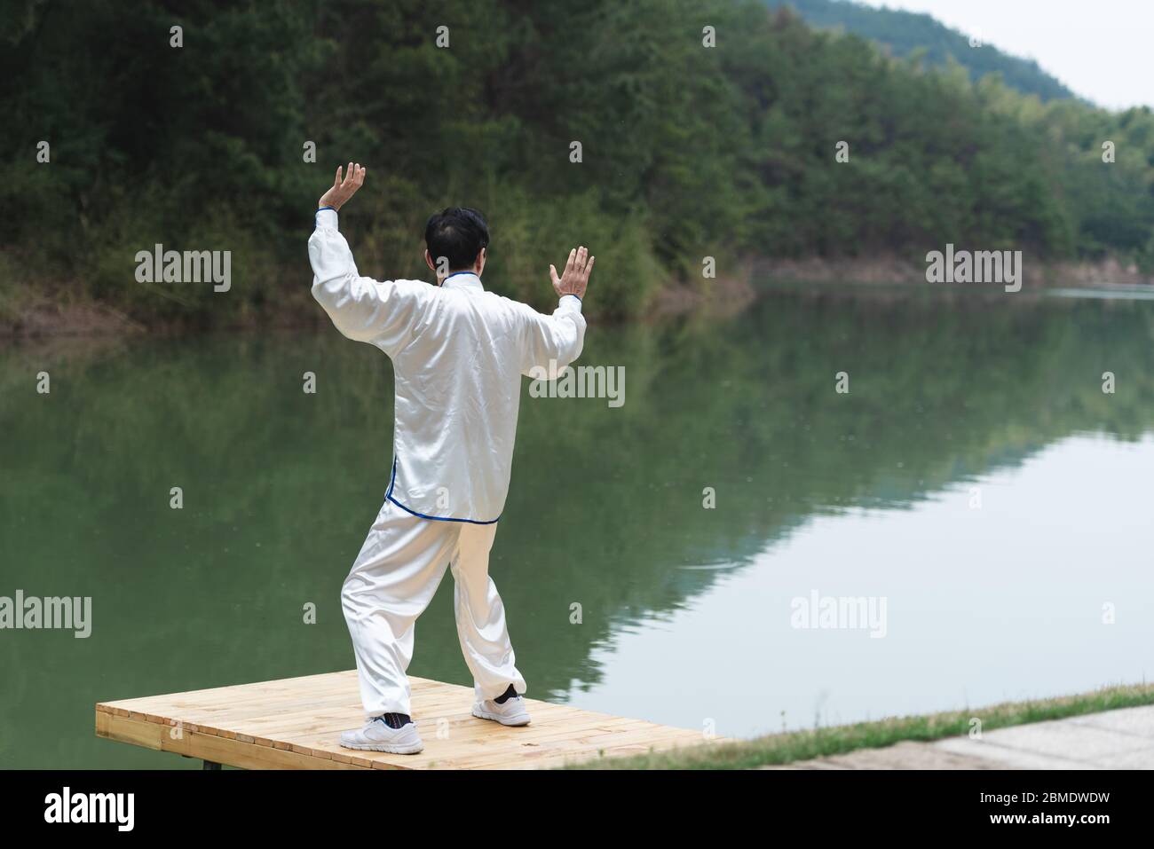 Un homme asiatique âgé faisant du sport au bord du lac Banque D'Images