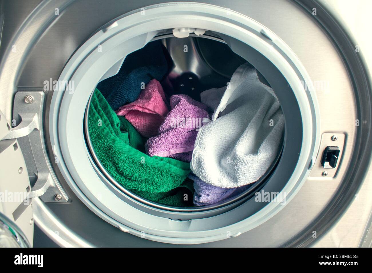 Homme prenant des vêtements de couleur de la machine à laver. Un tambour de  lave-linge plein de linge sale dans la salle de bains Photo Stock - Alamy