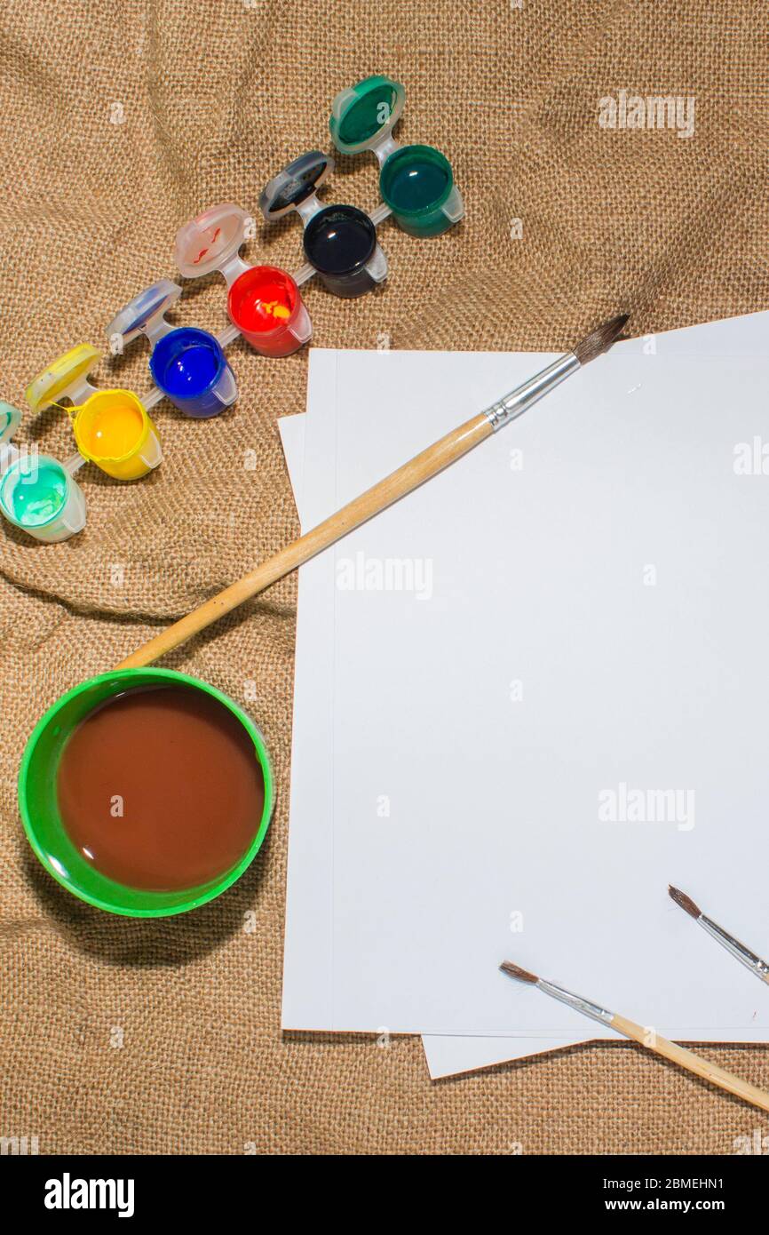 Ensemble de peintures aquarelles, pinceaux pour la peinture et feuille de papier blanc vierge de carnet d'esquisses. Vue de dessus. Banque D'Images