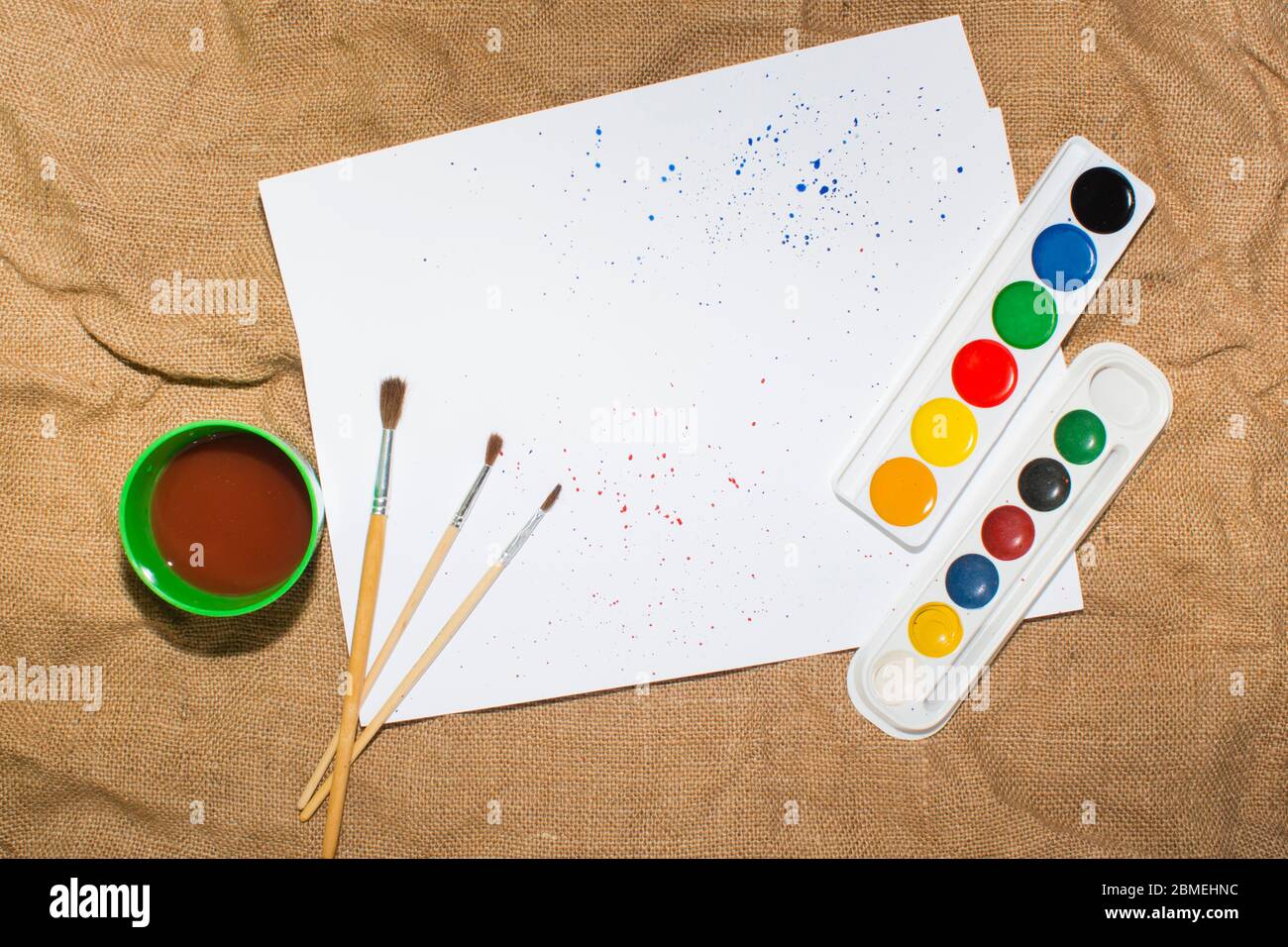 Ensemble de peintures aquarelles, pinceaux pour la peinture et feuille de papier blanc vierge de carnet d'esquisses. Vue de dessus. Banque D'Images