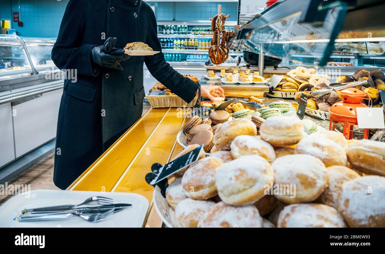 Paris, France - 9 décembre 2017 : vue latérale d'une femme élégante en manteau noir prenant de la cour de restauration à l'intérieur du restaurant de meubles IKEA un délicieux gâteau Banque D'Images