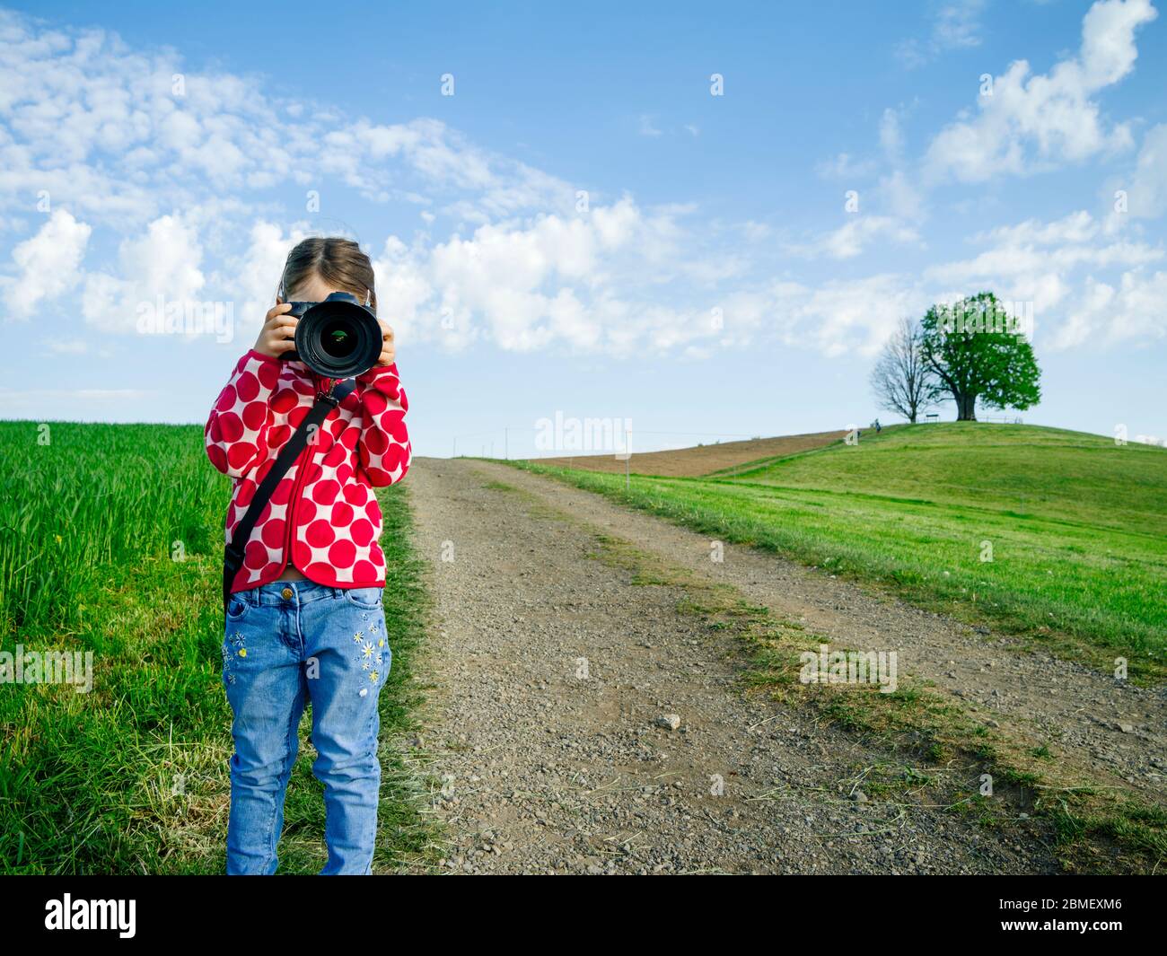 Jeune fille avec un grand appareil photo dans la Suisse rurale prenant des photos du paysage. Banque D'Images