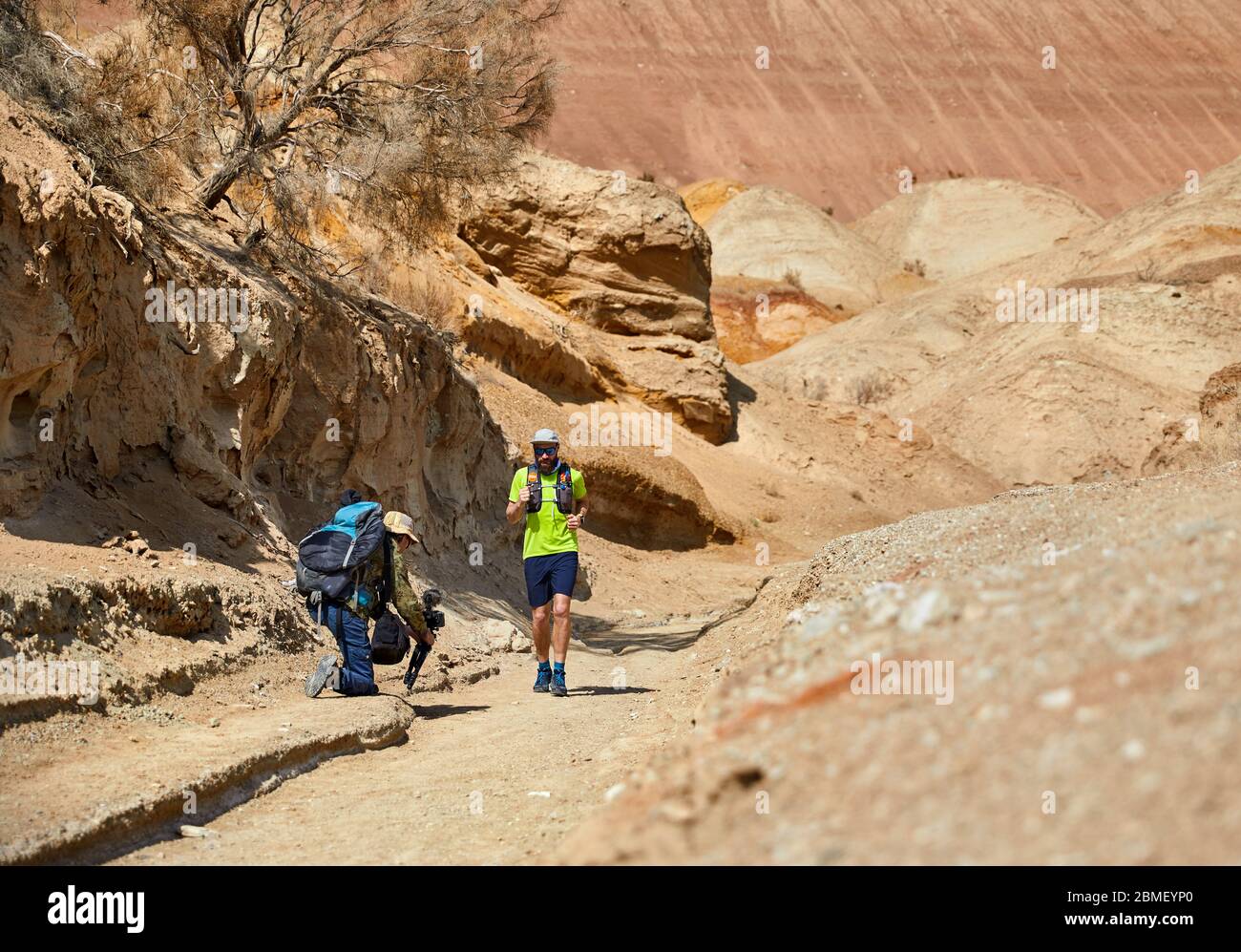 Prise de cinéaste documentaire sur l'athlète coureur sur la piste sauvage de montagnes d'argile dans le désert Banque D'Images