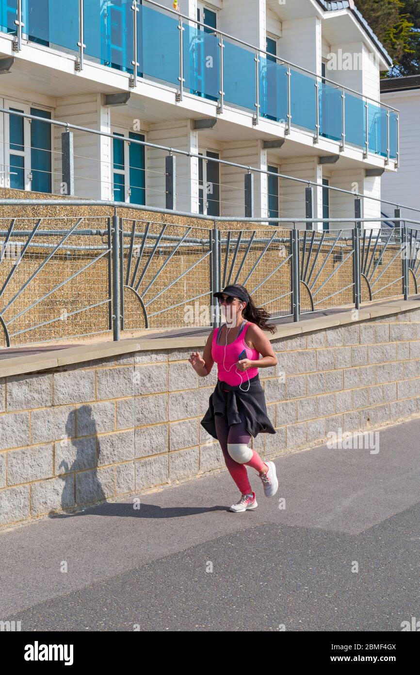 Poole, Dorset Royaume-Uni. 9 mai 2020. Météo au Royaume-Uni : chaud et ensoleillé à Poole - même pas 10 heures et les températures qui montent avec l'air complètement encore sur ce qui est prévu pour être le jour le plus chaud de l'année. Les gens se dirigent vers la mer avec le conseil patrouiller les plages et parler aux personnes qui ne sont pas là pour faire de l'exercice pendant le long week-end de vacances en banque. La plupart des gens sont là pour prendre leur exercice autorisé en respectant les directives du coronavirus. Femme qui court le long de la promenade le long des huttes de plage - coureur jogging jogging jogging course. Crédit : Carolyn Jenkins/Alay Live News Banque D'Images