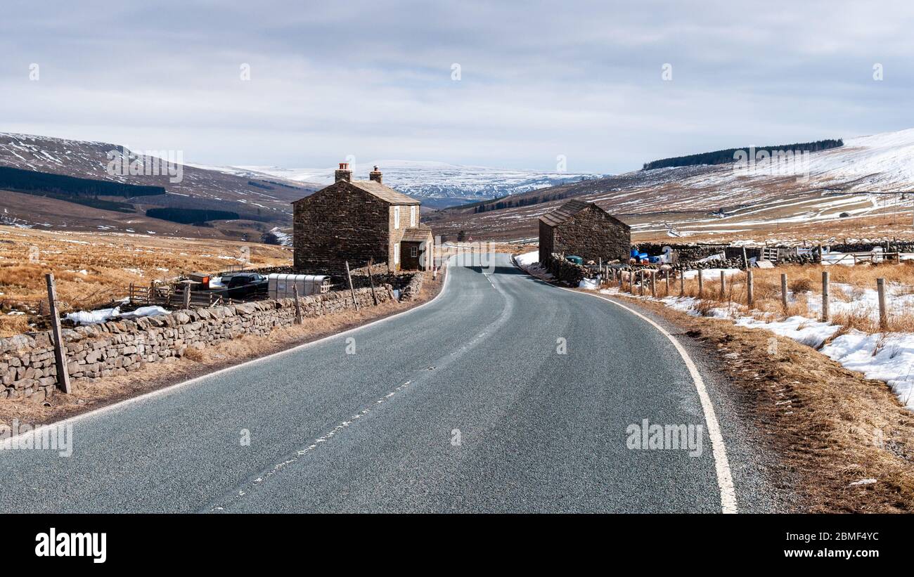 Hawes, Angleterre, Royaume-Uni - 1er avril 2013 : le soleil d'hiver brille sur une ferme et une grange en haut de la vallée de Widdale sous les collines des Yorkshire Dales. Banque D'Images