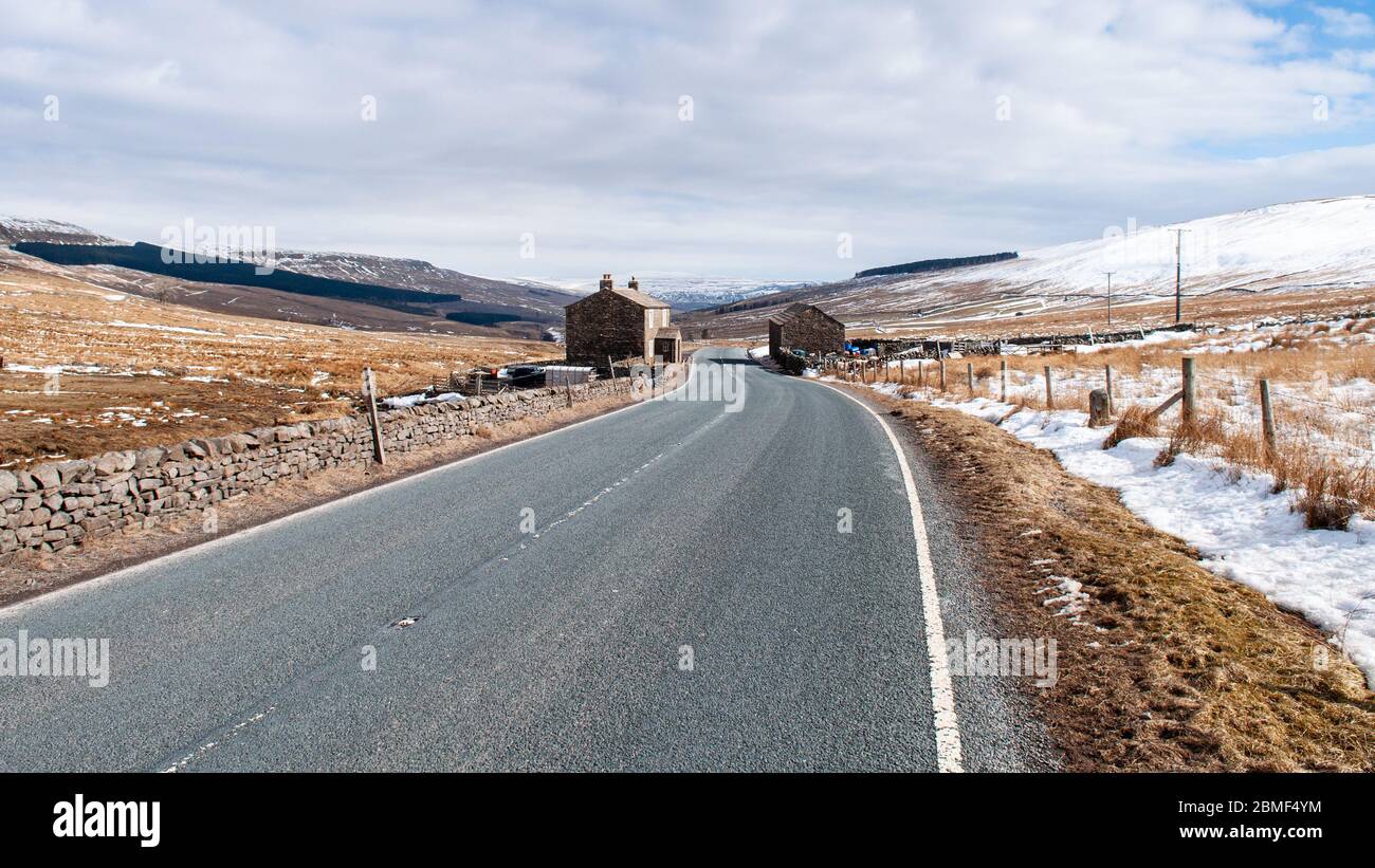 Hawes, Angleterre, Royaume-Uni - 1er avril 2013 : le soleil d'hiver brille sur une ferme et une grange en haut de la vallée de Widdale sous les collines des Yorkshire Dales. Banque D'Images