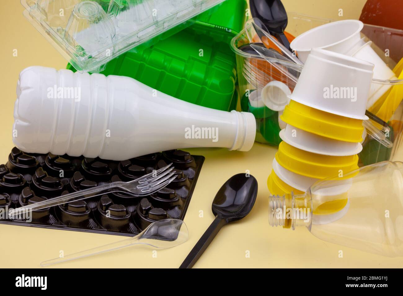 Tri des déchets. Déchets plastiques pour recyclage. Bouteilles en plastique, récipients, fourchettes, cuillères, emballages d'œufs, bouchons. Fond jaune avec met pour le texte Banque D'Images