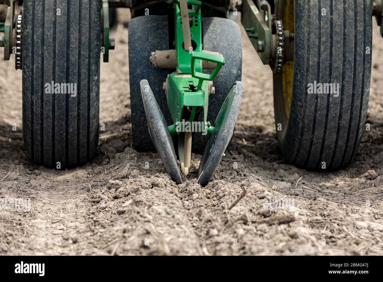 Gros plan du semoir dans les champs de ferme plantant du maïs ou des graines de soja dans un sol sec et poussiéreux pendant la saison de printemps Banque D'Images