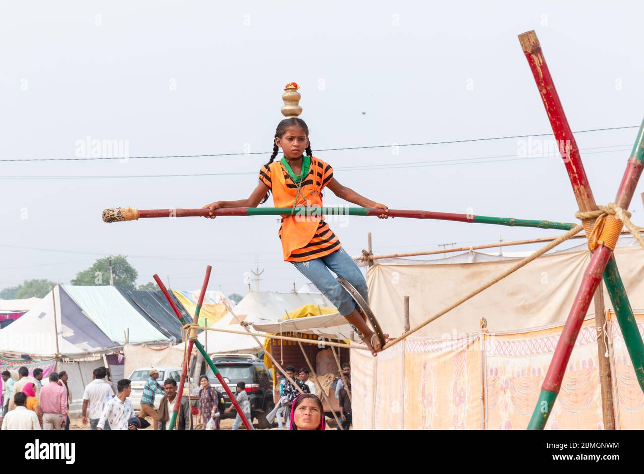 Jeune fille exécutant acrobaties dans corde serrée et l'équilibrage avec bambou à la Foire de Pushkar Banque D'Images