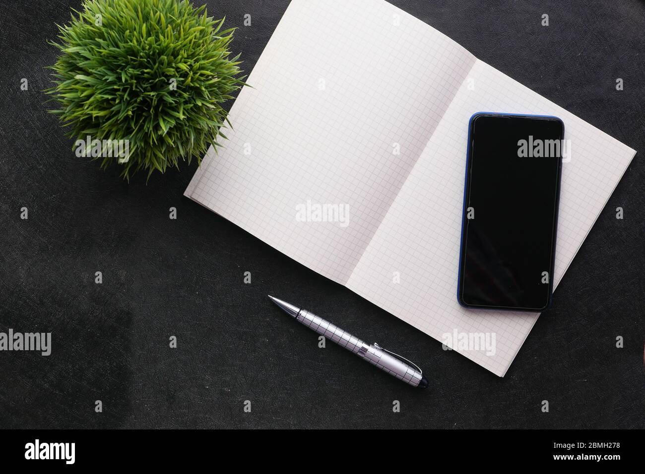 Vue de dessus du smartphone avec écran vide et bloc-notes sur fond noir Banque D'Images