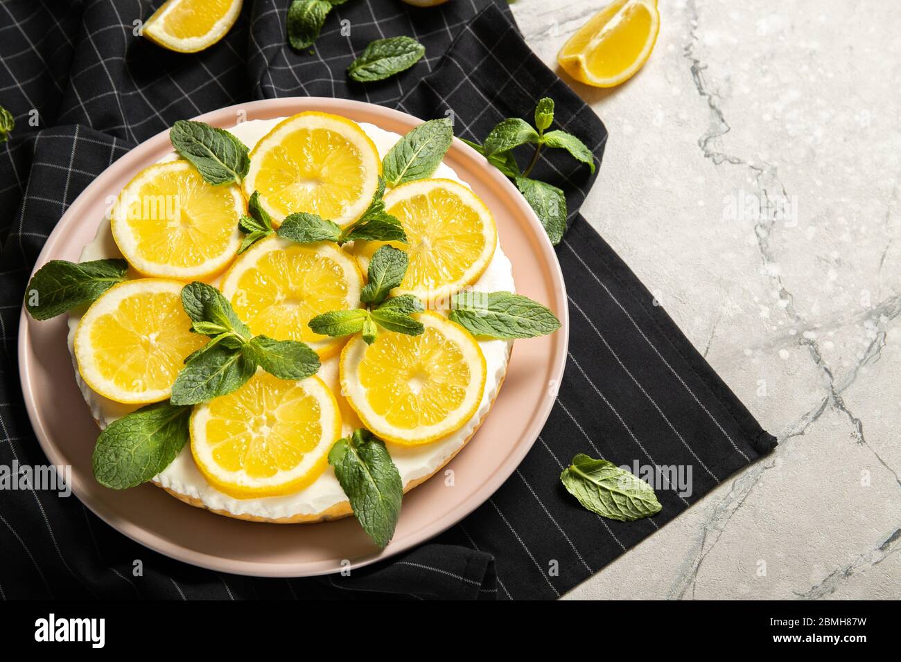 Assiette avec un délicieux cheesecake et des citrons sur la table Banque D'Images