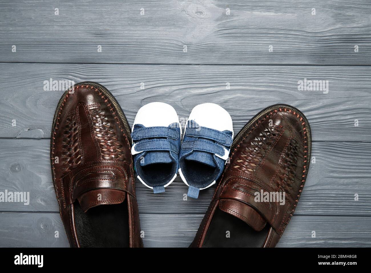 Concept de fête des pères heureux. Chaussures de papa et de petit fils sur fond de bois. Placer pour le texte Banque D'Images