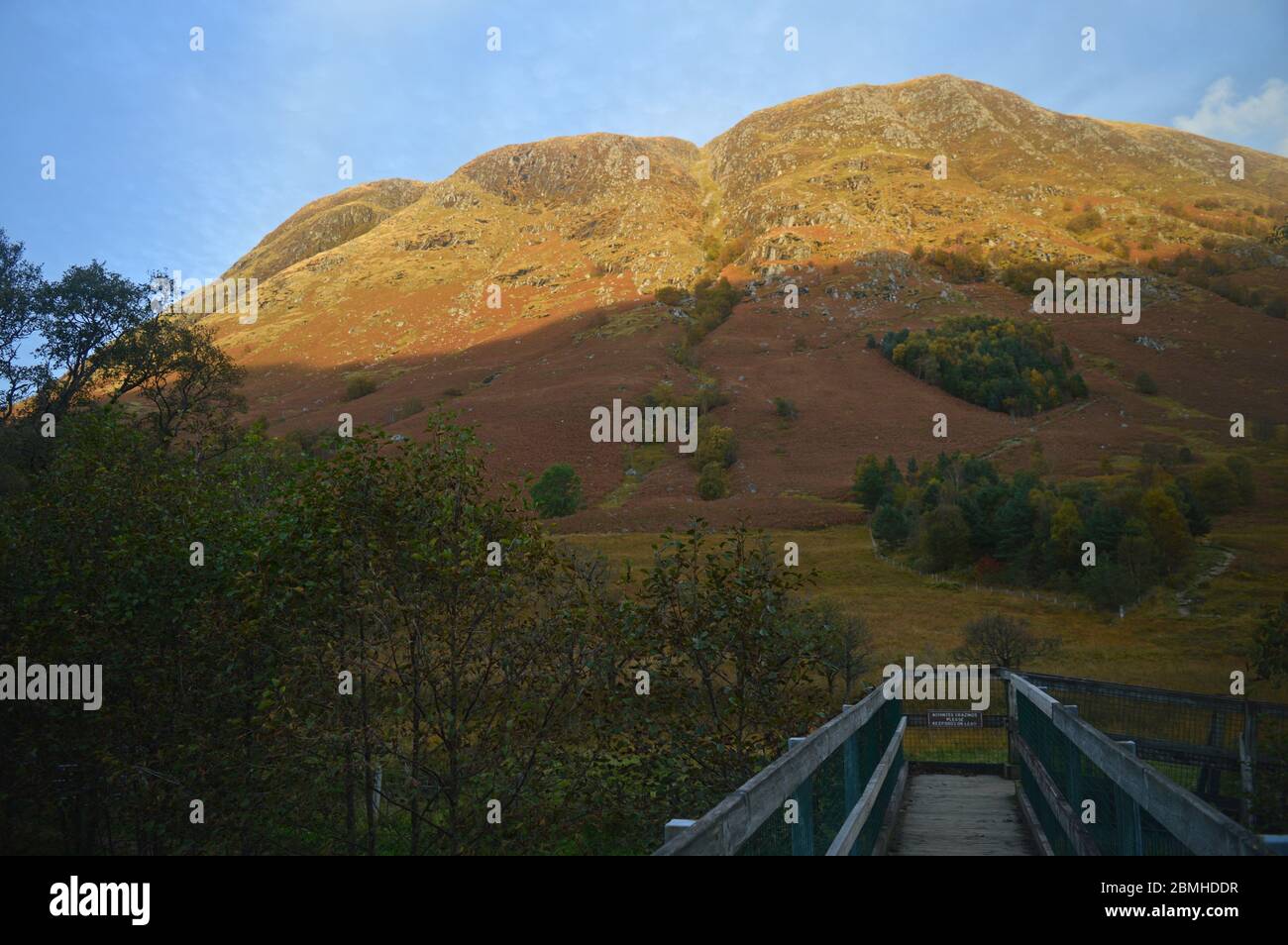 Passerelle à travers la rivière Nevis et pentes de la base de Ben Nevis en fin d'après-midi soleil d'automne Banque D'Images